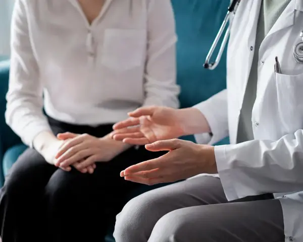 Lekarz omawia z pacjentem świadczenie rehabilitacyjne, gestykulując dłońmi.