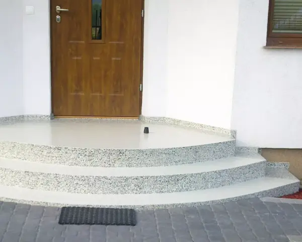 Schody i balkon z żywicy przed drzwiami wejściowymi do domu.