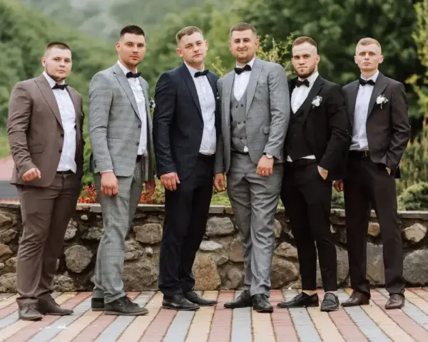 Sześciu mężczyzn w garniturach i białych koszulach, każdy z muszką. Różne kolory i wzory garniturów pokazują, jaka koszula do garnituru pasuje najlepiej.