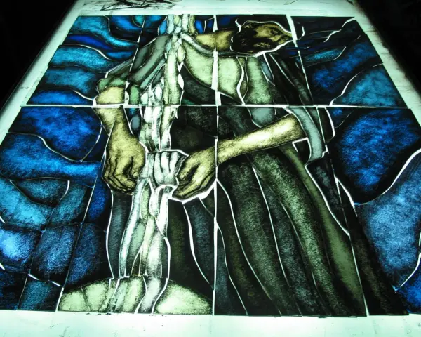 Fragment witrażu w stylu modernizm, przedstawiający postać w niebieskim i zielonym tle.