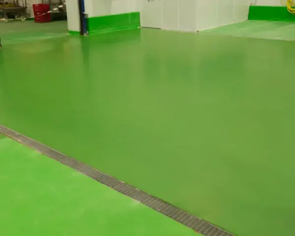 Un impecable pavimento industrial verde brillante, con una rejilla metálica a lo largo de una sección.