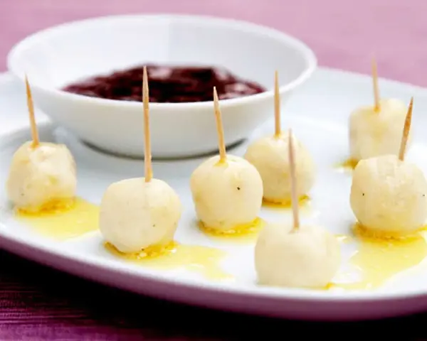 Små, gyllene kroppkakor med tandpetare, serverade med en skål mörk sylt. Ett spännande recept att prova!