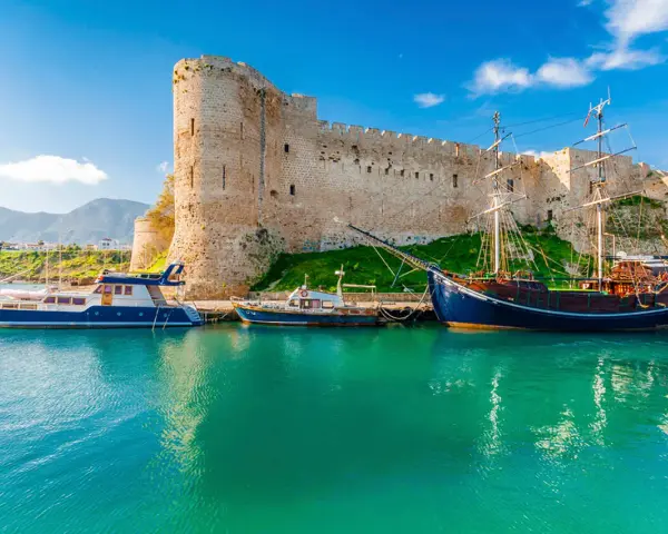 Zamek Kyrenia na Cyprze Północnym z łodziami przycumowanymi w turkusowej zatoce.