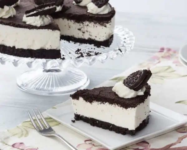 Una deliciosa tarta de oreo, con una base de galleta oscura y un cremoso relleno blanco, decorada con nata y galletas oreo.