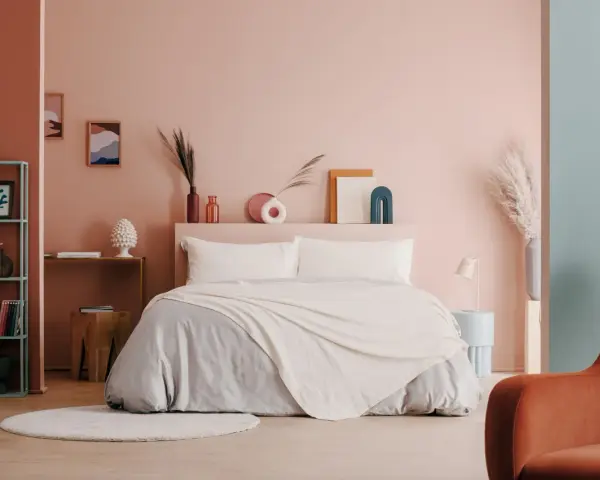 Camera da letto moderna con letto king-size, biancheria grigia e coperta color crema. Idee per come abbellire una camera da letto con decorazioni astratte e piante.