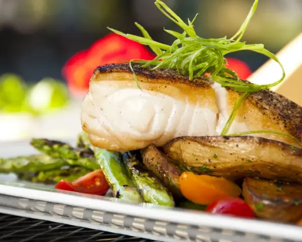 Aromatyczny halibut na talerzu z pieczonymi ziemniakami, szparagami i pomidorkami. Zapach halibut na jakie ryby?