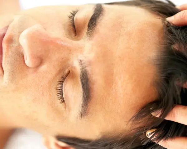 Fingers gently work through dark hair, demonstrating how to massage scalp for relaxation and hair health.