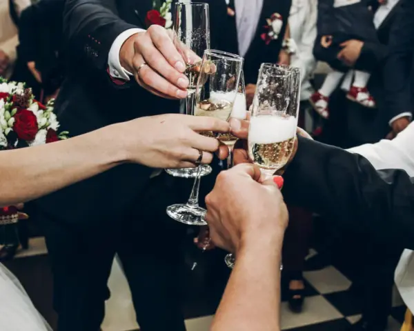 Wznoszenie toastu szampanem na weselu. Pytanie "ile wina na wesele" jest kluczowe, by wszyscy mogli się cieszyć.