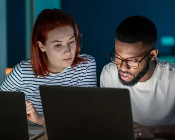 Zwei Personen arbeiten konzentriert an Laptops. Sie besprechen Details, vielleicht für einen partnerschaftsvertrag ohne notar.
