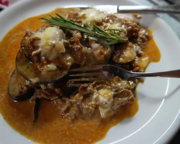 Herzhafte Auberginen-Hackfleisch-Auflauf, inspiriert von Omnia Rezepte, mit geschmolzenem Käse und Rosmarin garniert.