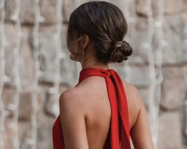 Elegante moño bajo en una mujer con vestido rojo, luciendo su espalda descubierta y un pendiente llamativo.