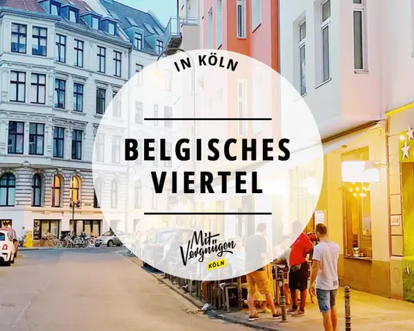 Abendstimmung im Belgischen Viertel in Köln. Menschen sitzen vor beleuchteten Geschäften, Autos parken am Straßenrand.