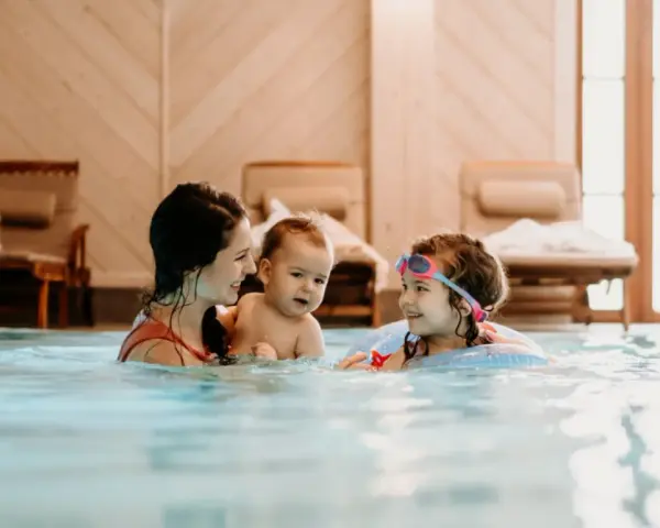 Rodzina cieszy się basenem w hotelu dla dzieci w Wiśle. Mama z dwójką dzieci pluska się w wodzie, tworząc radosne wspomnienia.