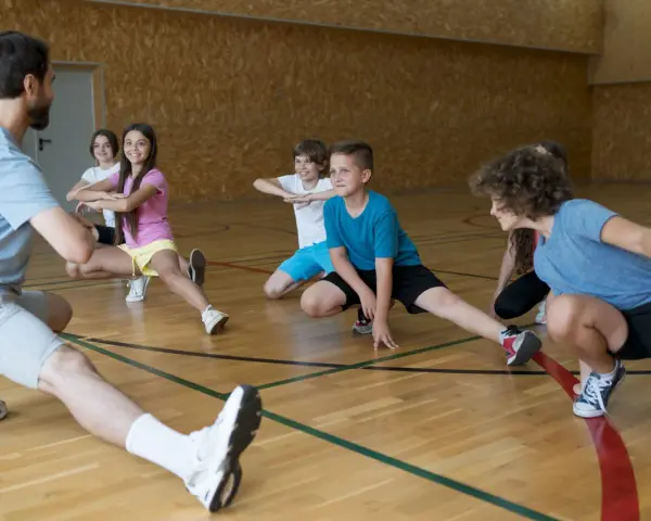 Un entraîneur guide des enfants lors d'une séance d'étirements. L'accueil des mineurs dans cette association sportive est une priorité.