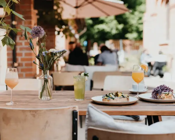 Leckeres Frühstück im 21 gramm Berlin: Toast mit Belag, Drinks & Blumen auf Holztisch.