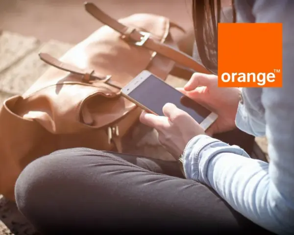 Kobieta z telefonem w dłoni, obok brązowa torba. Idealny dzień na środy z Orange.