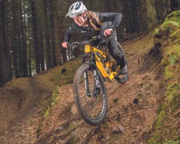 A mountain biker navigates a steep, wooded trail, showcasing the thrill of downhill mtb trails.