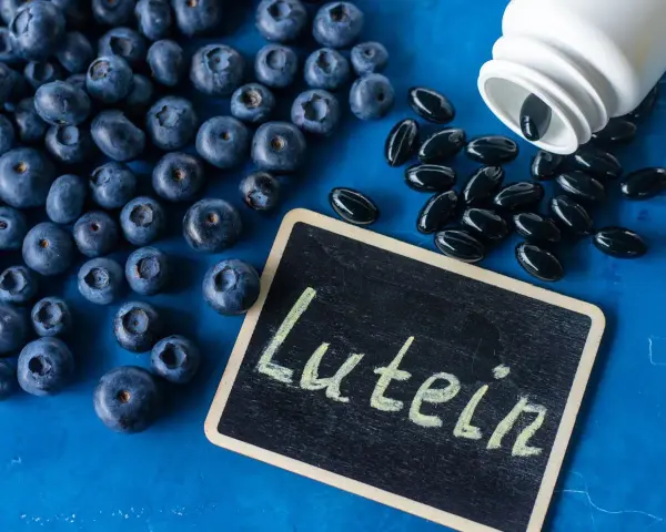 Borówki i kapsułki suplementu diety. Na tabliczce napis "Lutein". Luteina na co? Na zdrowie oczu!
