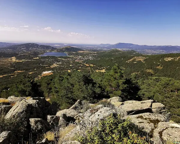 Vista panorámica del valle de la barranca, con un lago azul y montañas verdes bajo un cielo despejado.