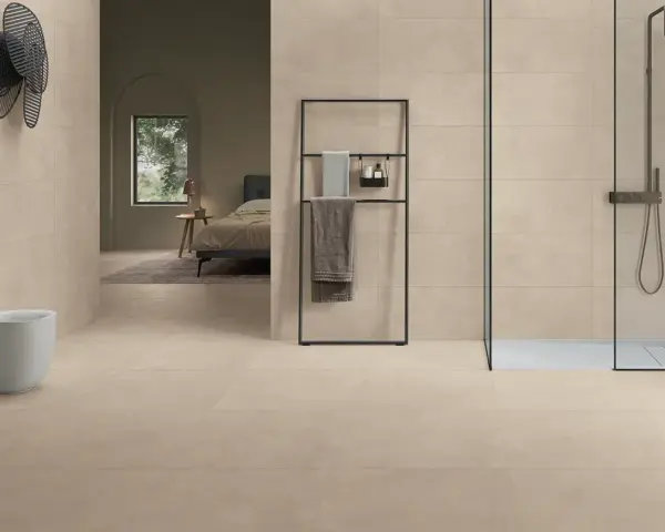 Salle de bain moderne avec bidet, douche et lit visible au loin, le tout revêtu de grès cérame émaillé.