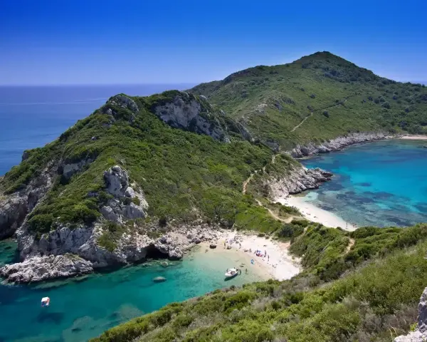 Malownicza zatoka z turkusową wodą i piaszczystą plażą, otoczona zielonymi wzgórzami. Tak właśnie wygląda Korfu, grecka wyspa, gdzie leży ten raj.