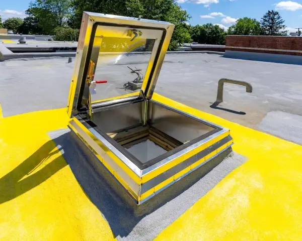 Porta di accesso al tetto aperta, con segnaletica gialla e grigia. La normativa per l'accesso al tetto è rispettata.