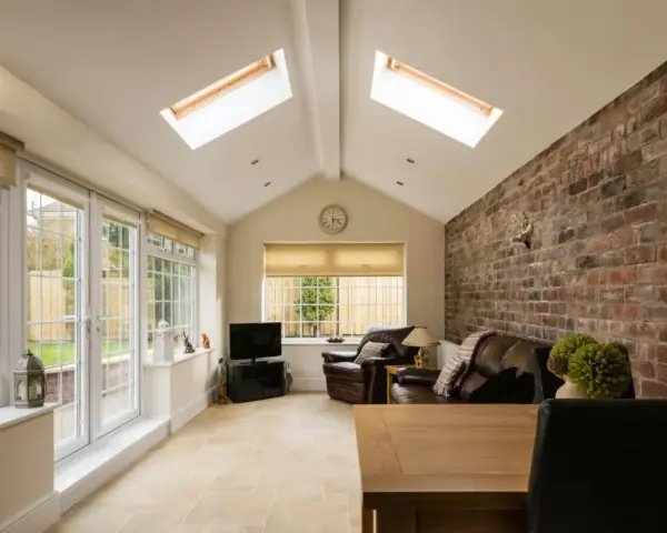 Salon lumineux avec murs en briques apparentes, baies vitrées donnant sur jardin. Idéal pour estimer le prix d'une extension 20m2 en parpaing.