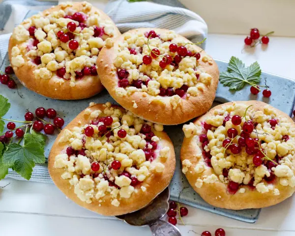 Vier kleine Küchlein mit Streuseln und roten Johannisbeeren, die den köstlichen jostabeere geschmack versprechen.
