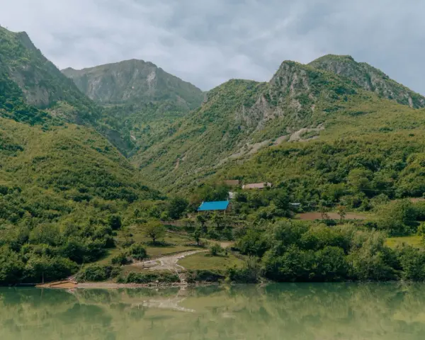 Zielone góry nad jeziorem, z domami i niebieskim dachem.