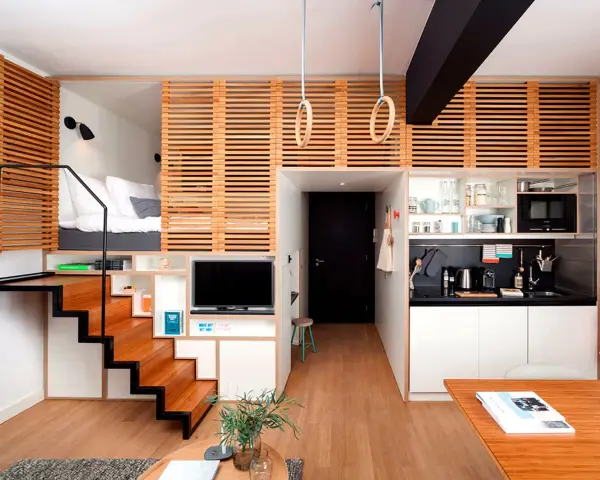 Acogedor apartamento con **dormitorios con techos altos** elevados, escaleras de madera, cocina compacta y zona de estar.