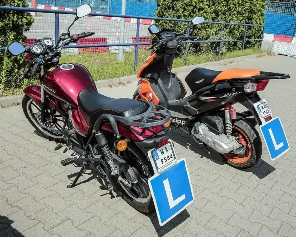 Dwa motorowery z literą "L" na tablicach, symbolizujące naukę jazdy. Od ilu lat można uzyskać kartę motorowerową?