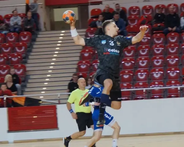 Kacper Grabowski w skoku do rzutu piłką ręczną, próbuje pokonać obronę przeciwnika.