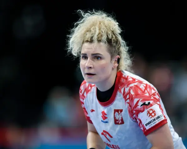 Sylwia Matuszczyk, zawodniczka w białej koszulce z czerwonymi wzorami, skupiona na boisku.