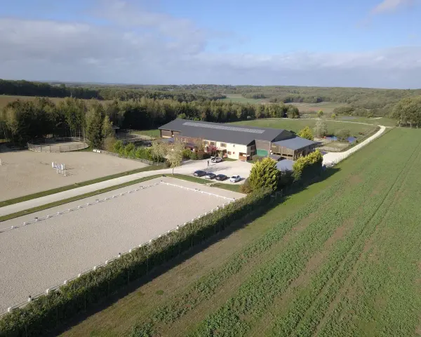 Vue aérienne d'une écurie avec manège et carrière de dressage. Le système de **carrière subirrigation** assure un sol parfait pour les chevaux.