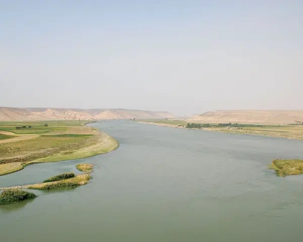 El río Éufrates serpentea entre fértiles campos verdes y áridas colinas.