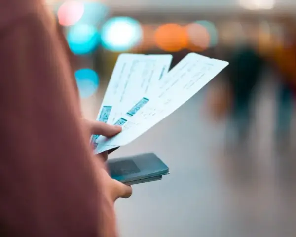 Dłoń trzyma bilety lotnicze i paszport. Może to być sytuacja związana z planowaniem podróży lub procesem **Ryanair zwrot biletu**.