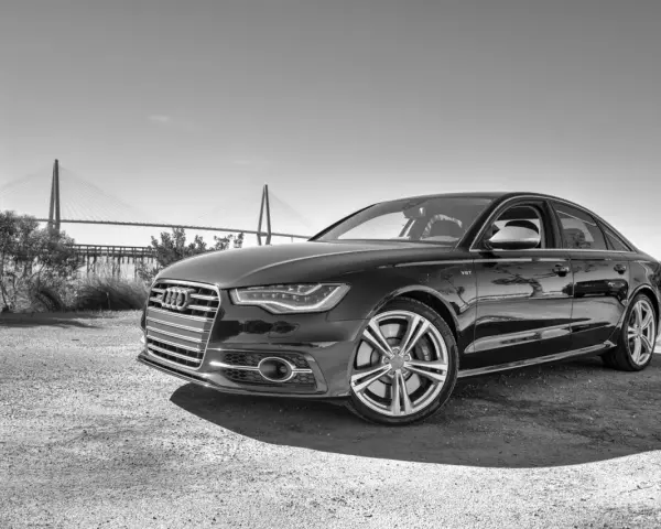 Elegancki czarny Audi S6 C7 z charakterystycznym grillem i felgami, zaparkowany na tle mostu wiszącego.