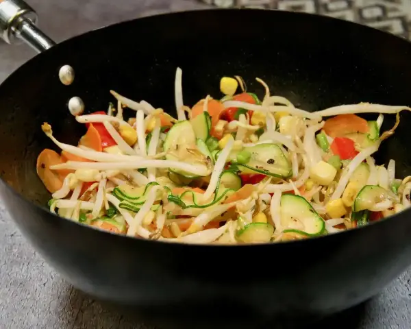 Kolorowe warzywa teriyaki w woku: kiełki fasoli mung, cukinia, marchewka, papryka i kukurydza.