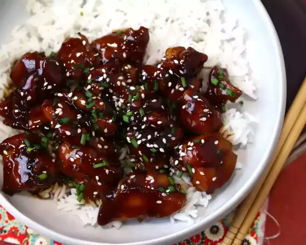Aksamitny teriyaki kurczak w sosie, posypany sezamem i szczypiorkiem, podany na białym ryżu. Pyszne danie gotowe do spożycia.