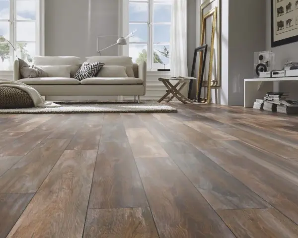 Sala de estar moderna con suelo de tarima AC5 de aspecto madera desgastada, sofá beige, alfombra y pufs.
