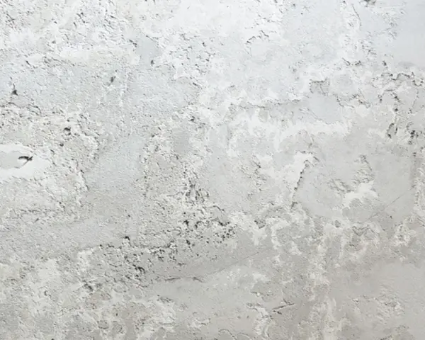 Textura de pared con manchas blancas y grises, como si la pintura se estuviera descascarando.