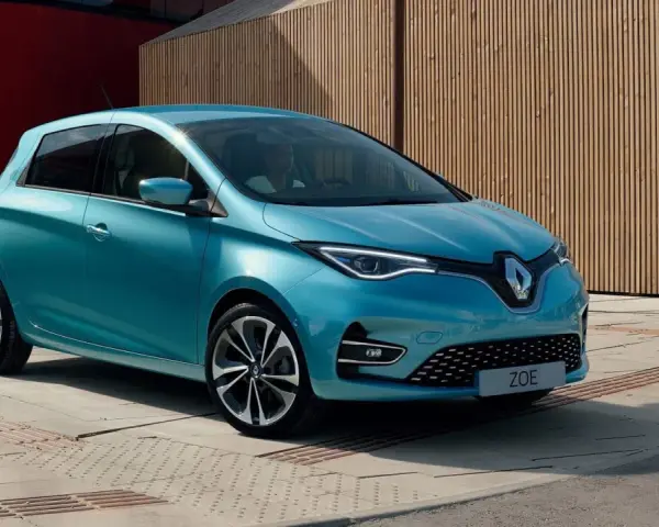 Błękitny Renault Zoe z nowoczesnymi światłami LED stoi na tle drewnianej elewacji.