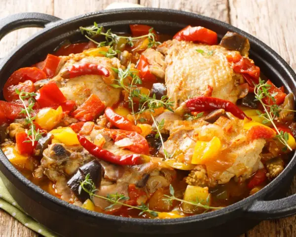 Sobracosce di pollo stufate con peperoni, pomodori, melanzane e peperoncino, guarnite con timo fresco.