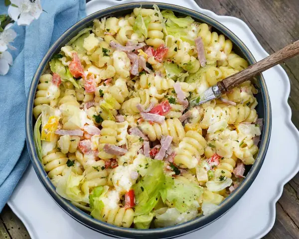 En krämig pastasallad med skinka, grönsaker och en dressing baserad på olja. Perfekt till sommaren!