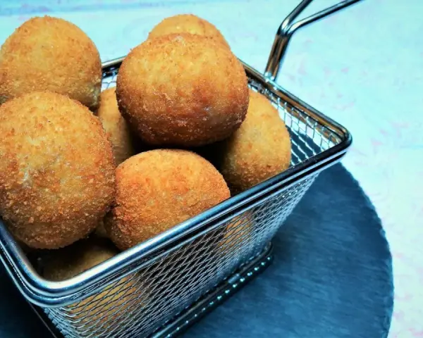 Croquetas doradas y crujientes en una cesta metálica.