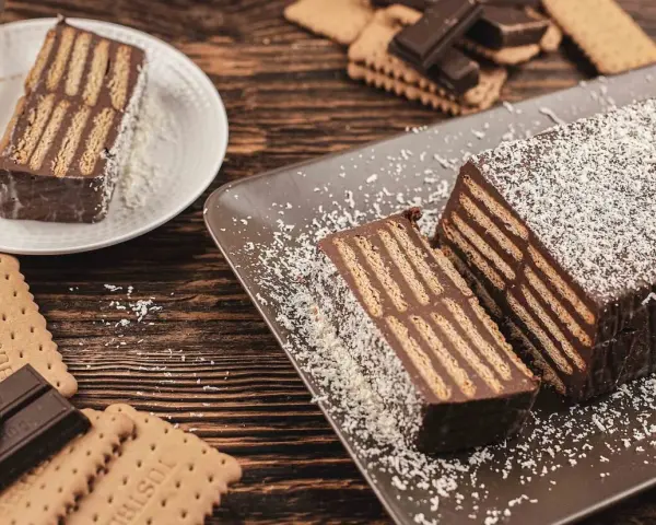 Tarta de chocolate y galletas, un postre casero con capas de galletas y crema de chocolate, espolvoreada con coco rallado.