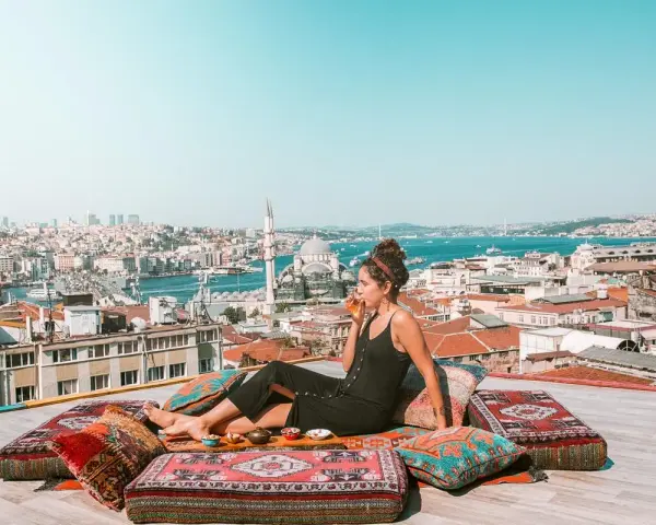 A woman enjoys a drink on a rooftop overlooking Istanbul, a scene straight out of a Rick Steves Turkey adventure.