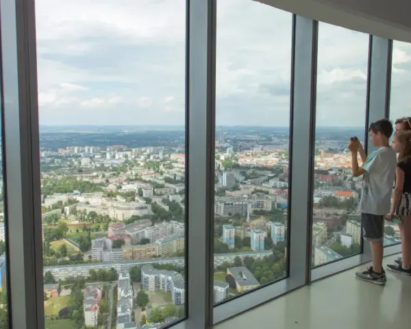 Widok z tarasu widokowego Sky Tower. Rodzina podziwia panoramę miasta, doceniając jego ogromną wysokość.