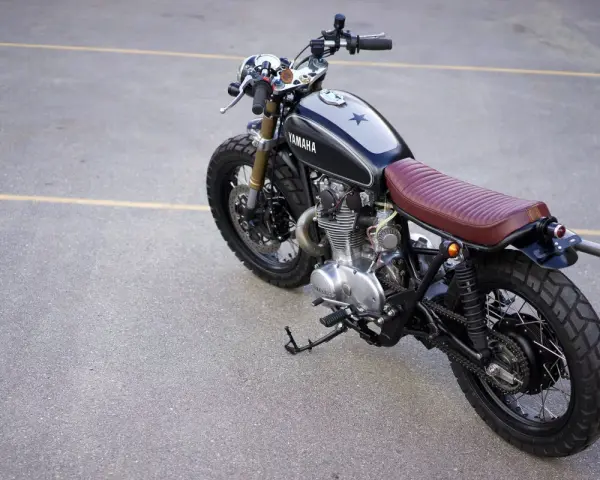 Klasyczny motocykl Yamaha z brązowym siedzeniem i gwiazdą na baku. Kraj pochodzenia tego modelu to Japonia.