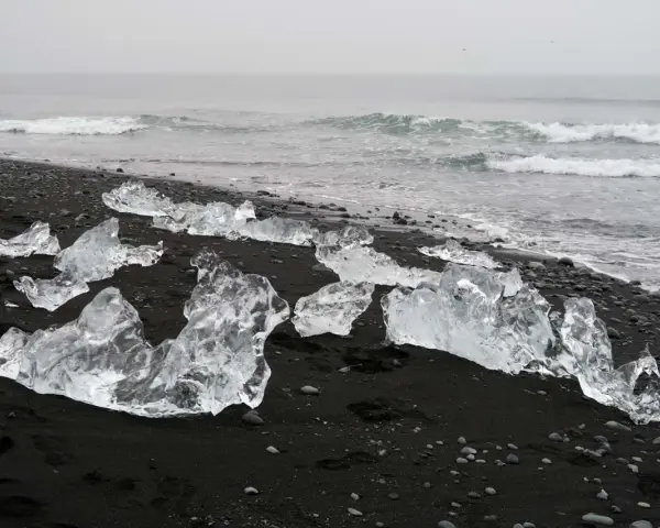 Lodowe bryły na czarnym piasku tworzą magiczną diamentową plażę Islandii. Fale oceanu delikatnie obmywają ten niezwykły krajobraz.